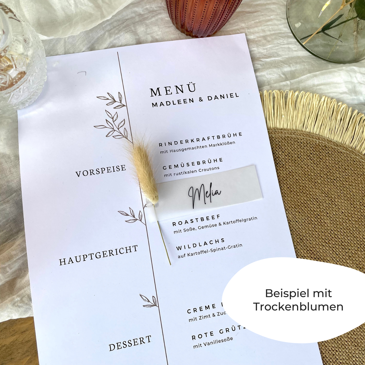 Transparentes Namensschilder mit der Aufschrift "Melia" an einer Trockenblume gebunden, als Bespiel