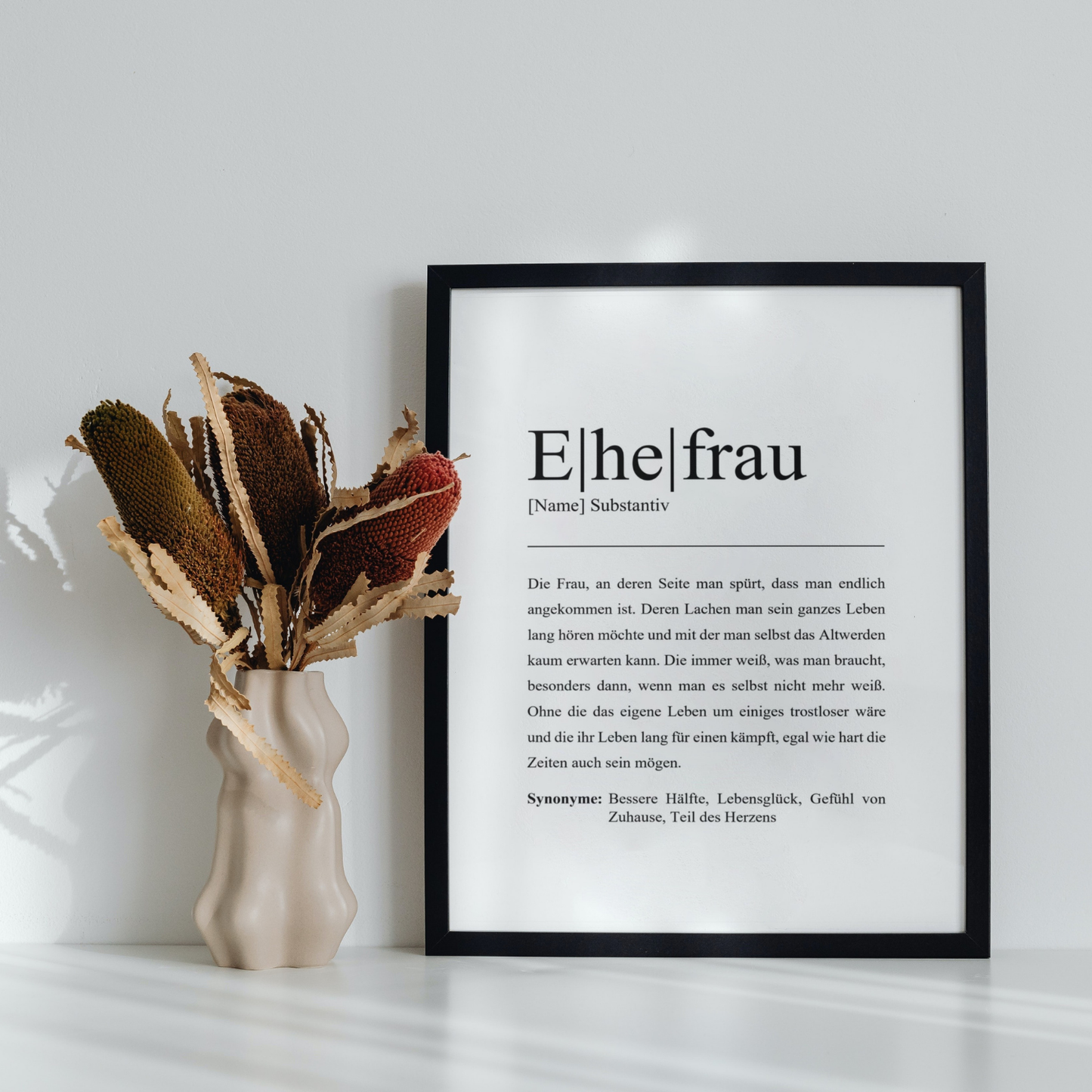 Zeitloses Ehefrau Poster im schwarzen Rahmen neben Trockenblumen Vase. Perfektes Geschenk für die Frau oder Partnerin. Stilvoll und individuell, ideal für kreatives Zuhause Dekor.
