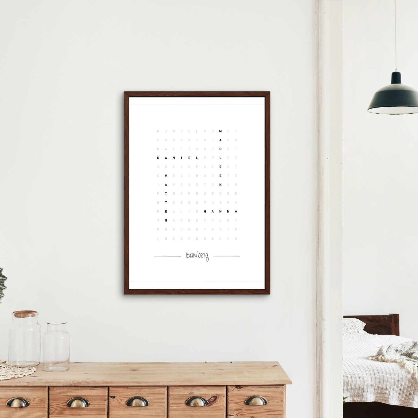 Minimalistisches Poster im Wortsuche-Design mit einem edlen Holzrahmen. Es hängt an einer weißen Wand über einer Kommode mit Naturdeko. Eine stilvolle Ergänzung für moderne und gemütliche Räume in Bamberg.