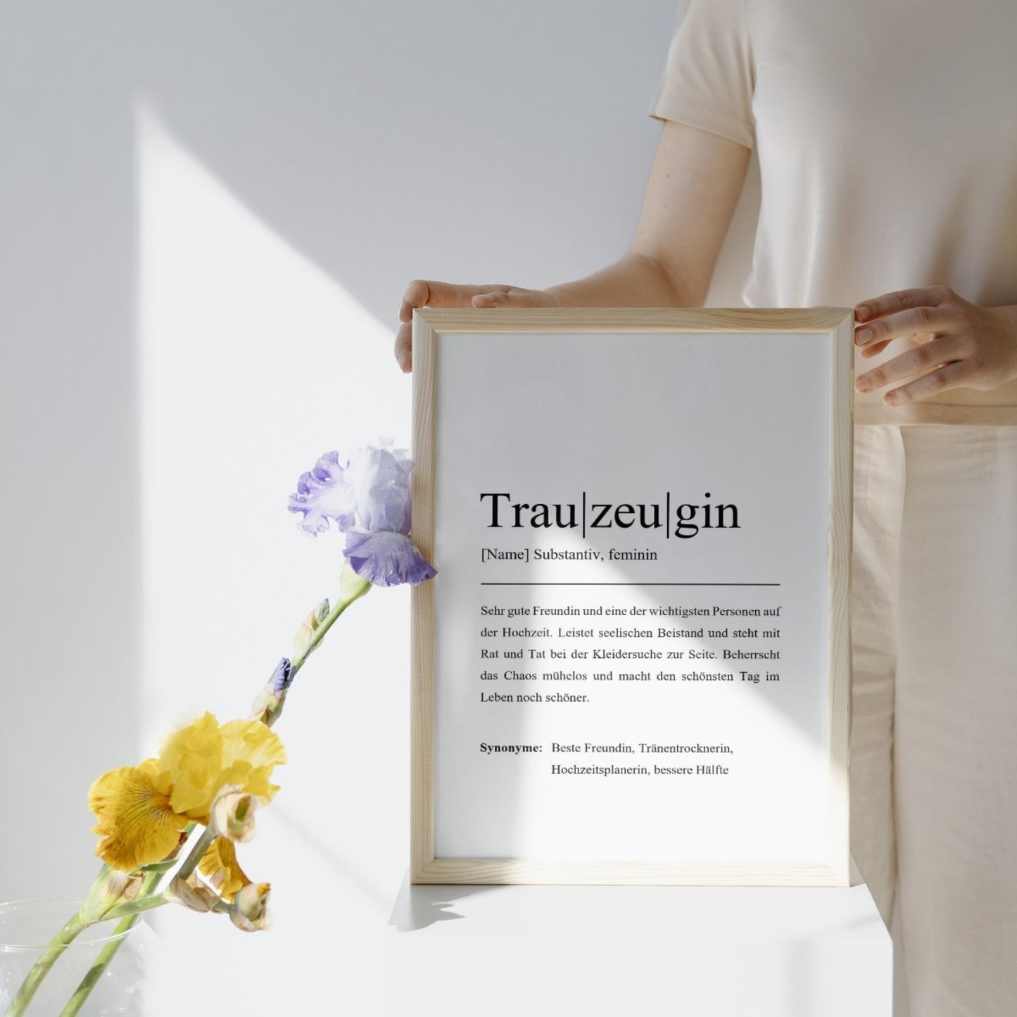 Person in heller Kleidung hält ein Trauzeuginnen-Poster mit Holzrahmen, nebenan eine Vase mit erfrischenden Blumen. Stilvoll und personalisierbar, perfekt als Hochzeitsgeschenk.