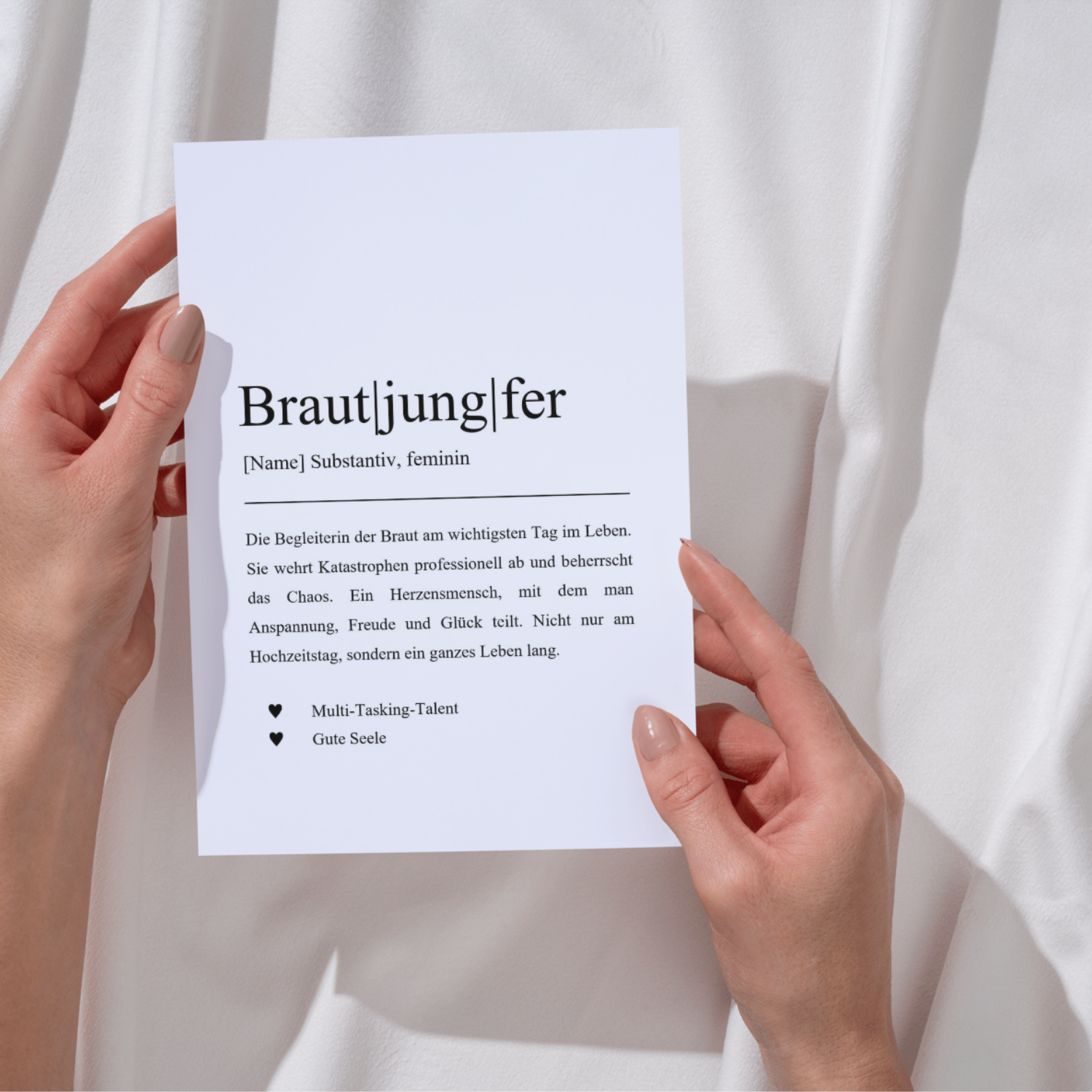 Definition der Brautjungfer als humorvolle Karte, die ihre Rolle bei Hochzeiten beschreibt. Zwei Hände halten die Karte vor einem weißen Hintergrund. Perfekte Geschenkidee für Junggesellinnenabschiede und um Dankbarkeit auszudrücken.